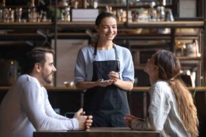 Happy restaurant employee with clients