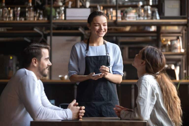 Happy restaurant employee with clients