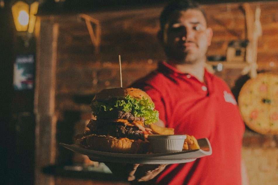 A waiter in the restaurant serves a hamburger